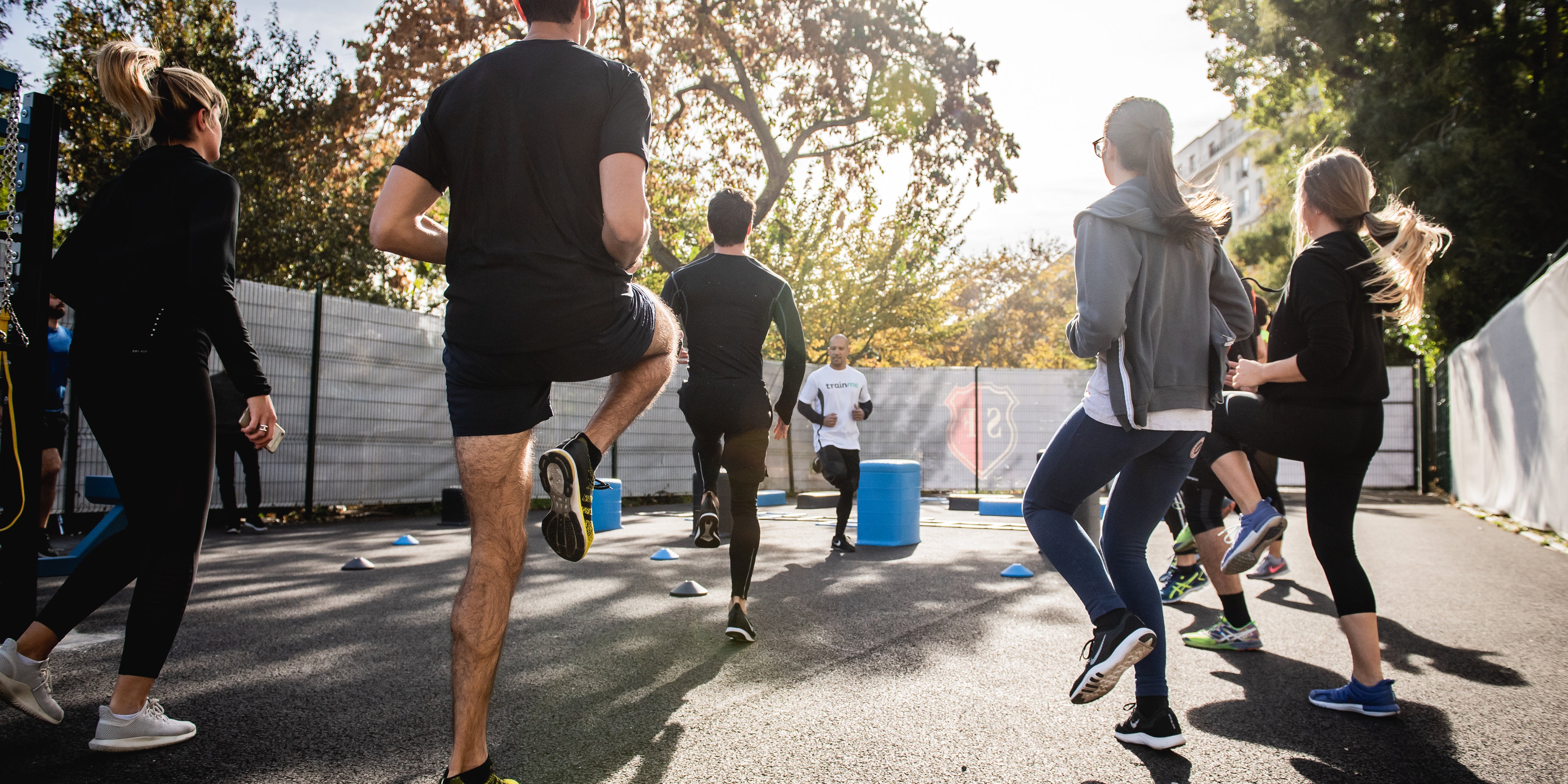 Group of people stand facing a fitness instructor